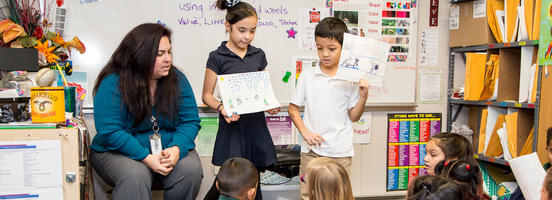 Two students in front of the class with the teacher